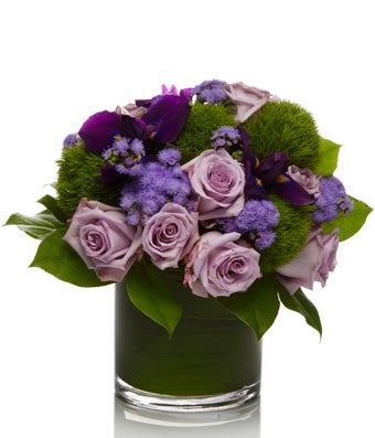 A classic arrangement of purple roses arranged with elegant greens and seasonal fillers.