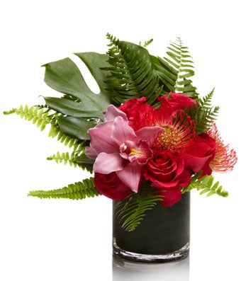 An exotic blend of pink roses, orchids, and other tropical seasonal flowers with modern greenery.