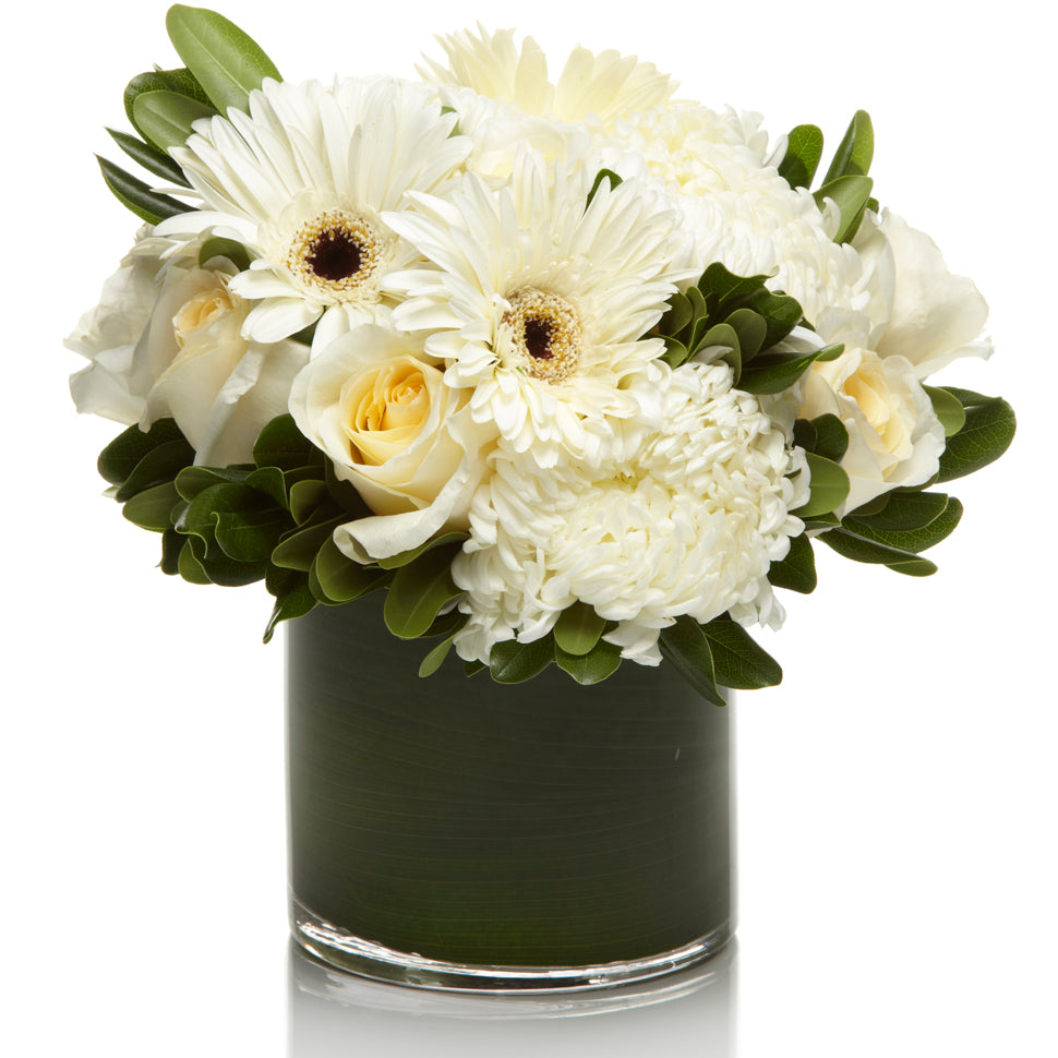 A mixed arrangement of white roses, daisies, and mums accented with greens.