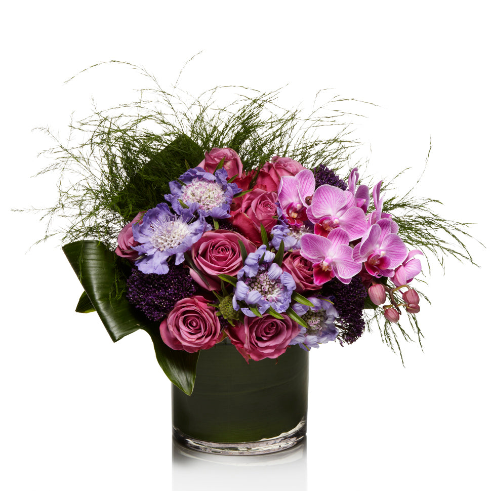 A Garden -Style Arrangement of Lavender, Purple and Pink Seasonal Blooms with Exotic Greenery - H.Bloom