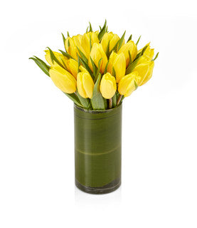 A classic arrangement showcasing yellow tulips in a glass hurricane vase.